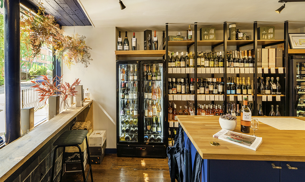 A shop front for a wine store with open shelves fileld with bottles